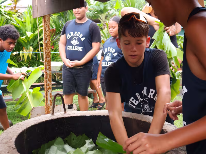 Youth laying down an umu 