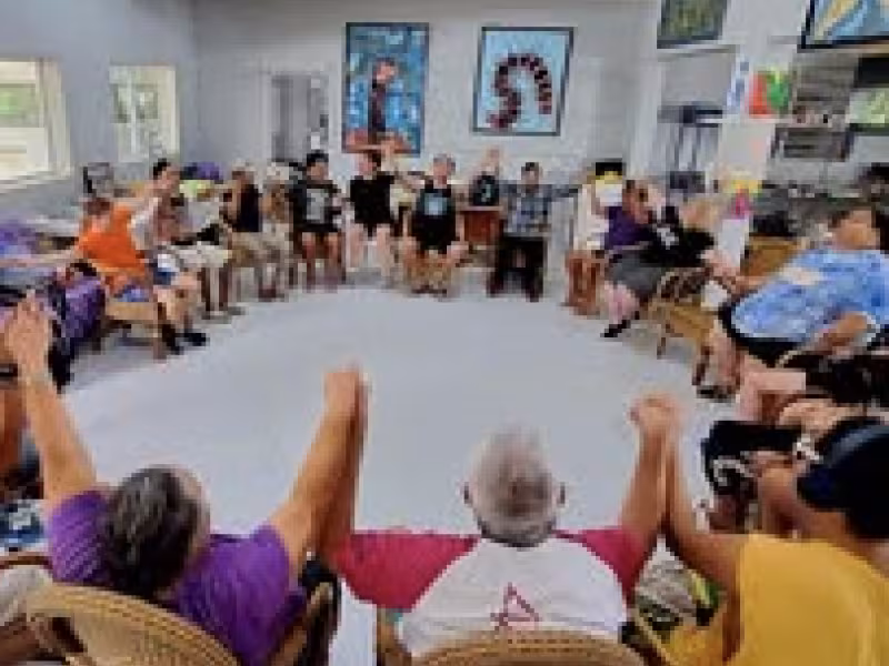 A picture of a group of people sitting holding hands in a circle 