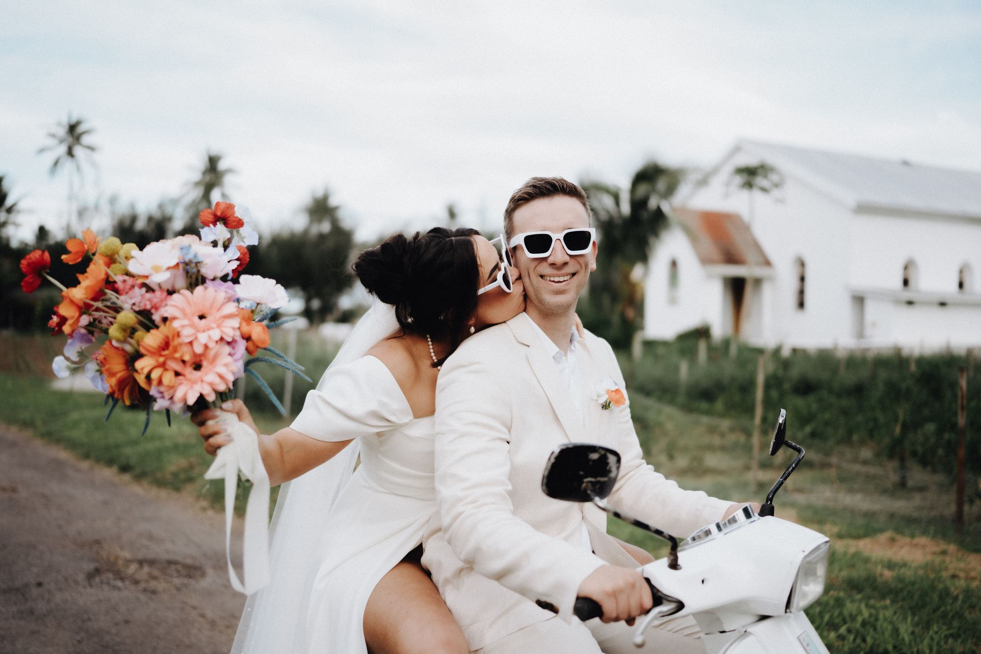 Wedding couple on scooter with bright flowers