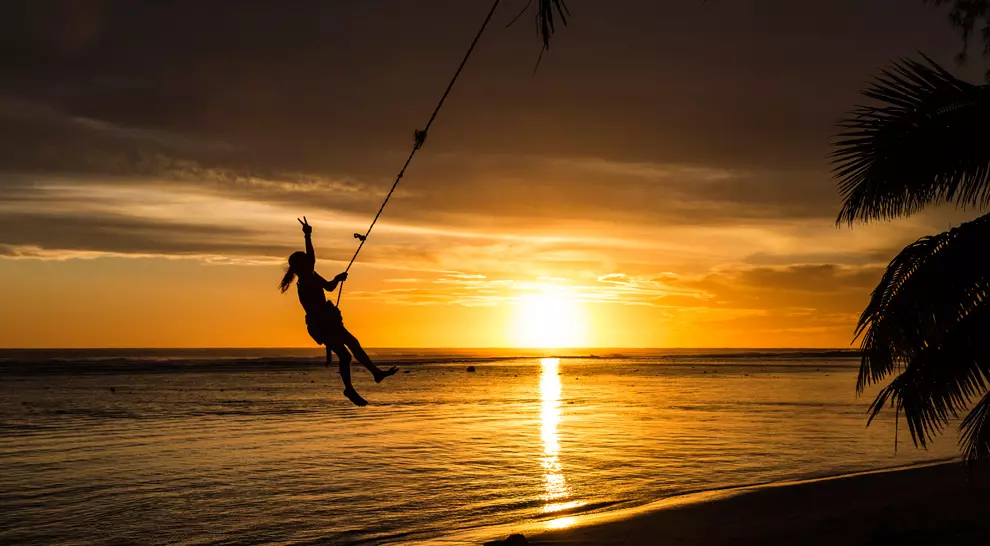 Young girl on a rope swing at sunset