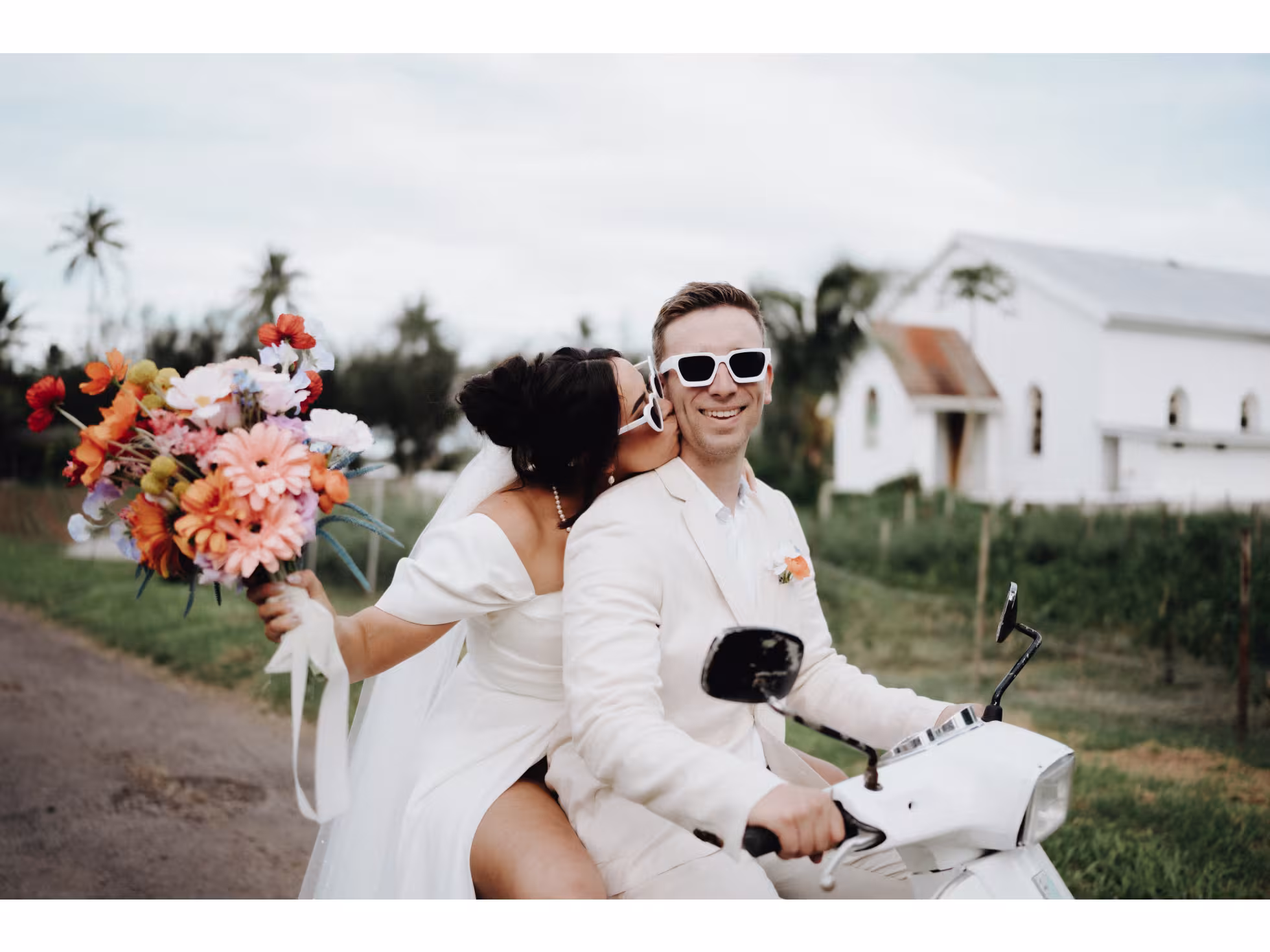 Wedding couple on scooter with bright flowers