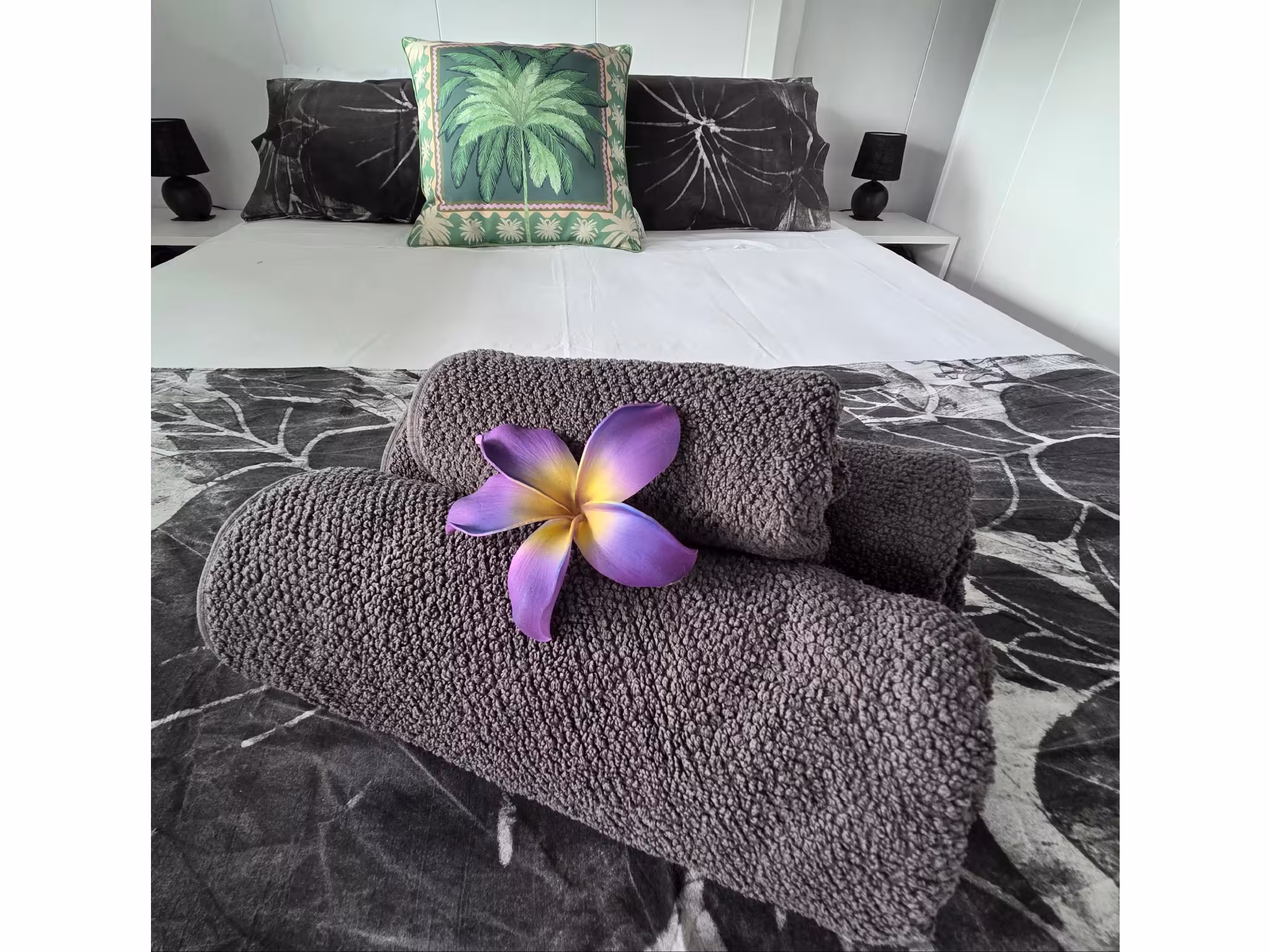 View of bed with towels and flower